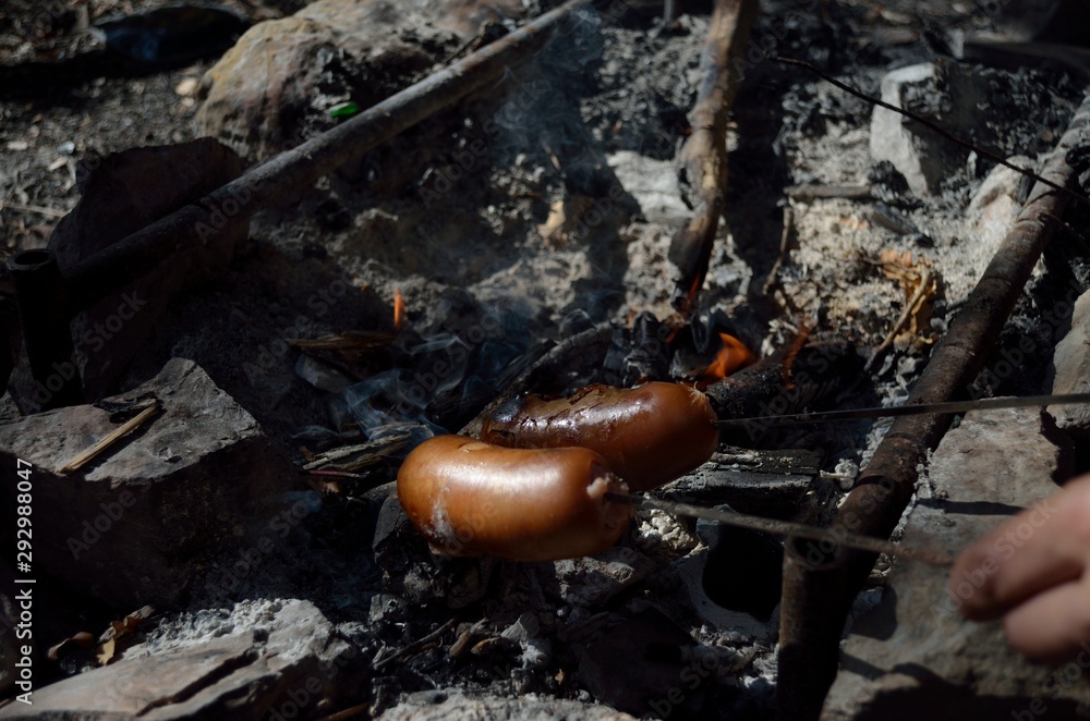 Roasted sausages on a stick over the open campfire. Outdoor food preparation. Roasted sausages on a stick over the open campfire. Outdoor food preparation.