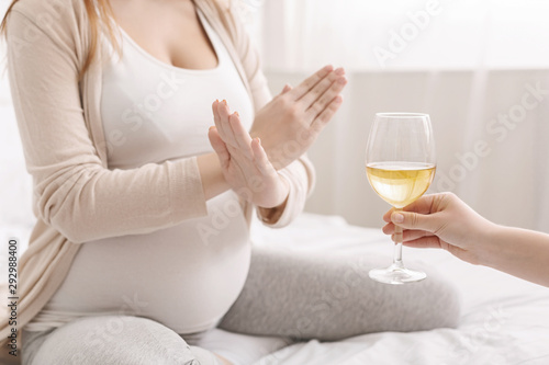 Pregnant woman with crossed hands refusing to drink wine