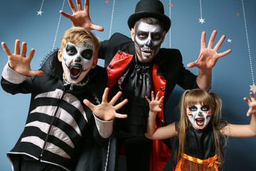 Father with children in Halloween costumes on color background