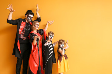 Family in Halloween costumes on color background