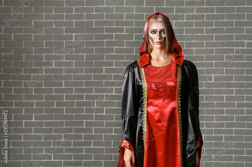 Young woman in Halloween costume on brick background