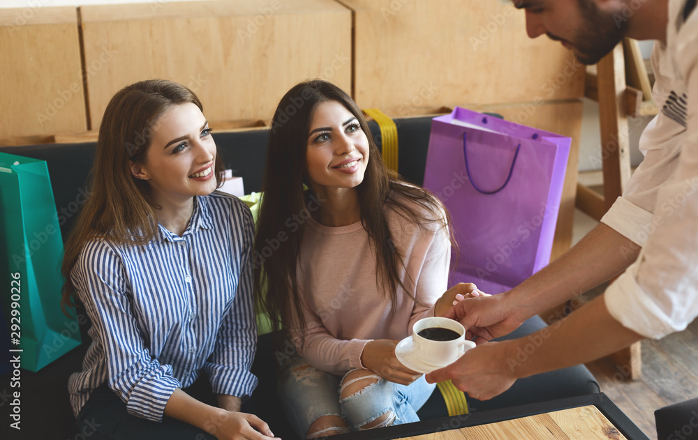 Εκτύπωση καμβά Waiter bring coffee for two cheerful girls in cafe after shopping