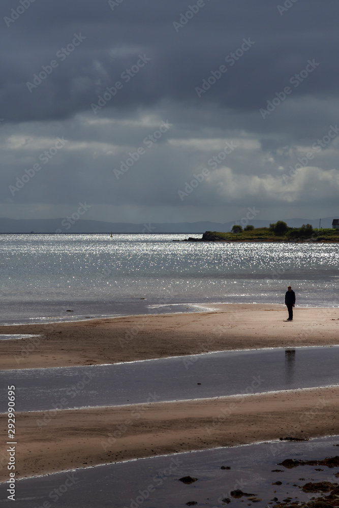 beach and man in sunlight at whiting bay on arran