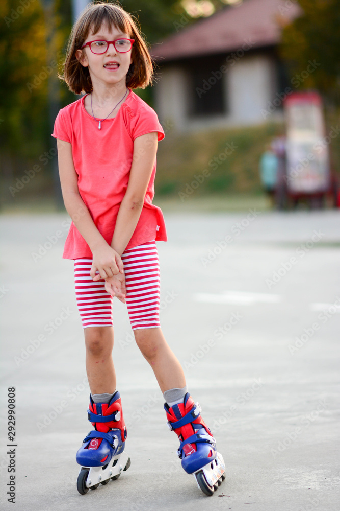 Little girl riding on roller skates outdoor. Happy young girl learning to  rollerblade. Kid wearing rollerblades, blue and red inline skates.  Vertical. Stock Photo | Adobe Stock