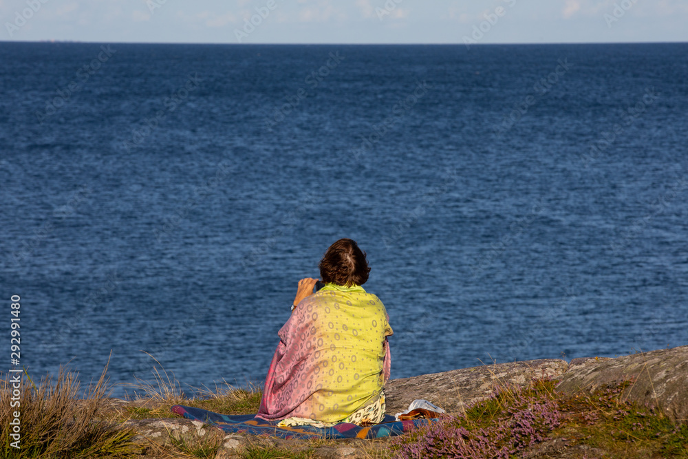 woman sits at the Baltic sea on the island of Bornholm