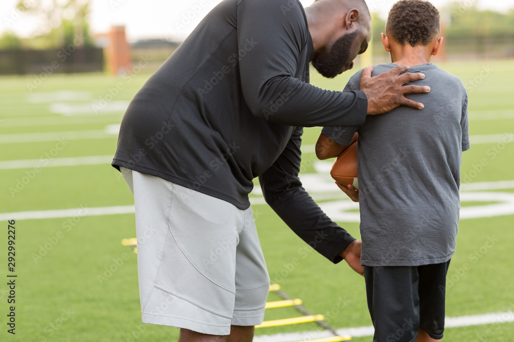 American Football coach training a young athlete. American Football coach training a young athlete.