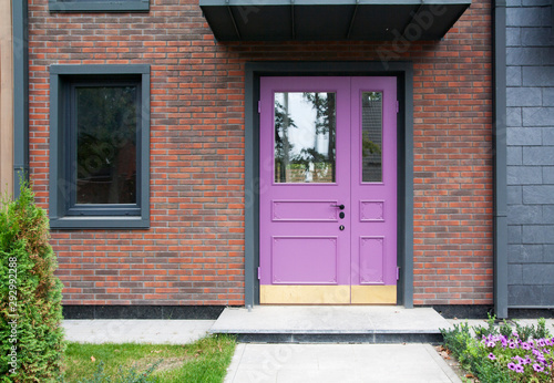 Original lilac front door and window on the background of decorative brickwork