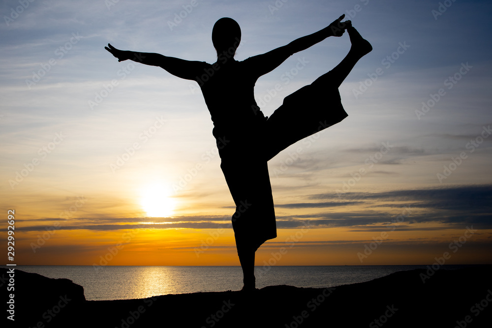 silhouette of woman at sunset, yoga position against the setting sun on the island of Bornholm, Denmark silhouette of woman at sunset, yoga position against the setting sun on the island of Bornholm, Denmark