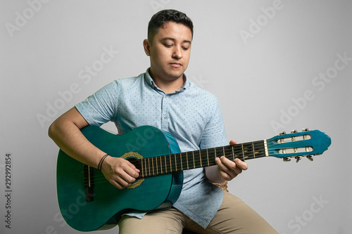 Boy playing acoustic guitar on a bench photo