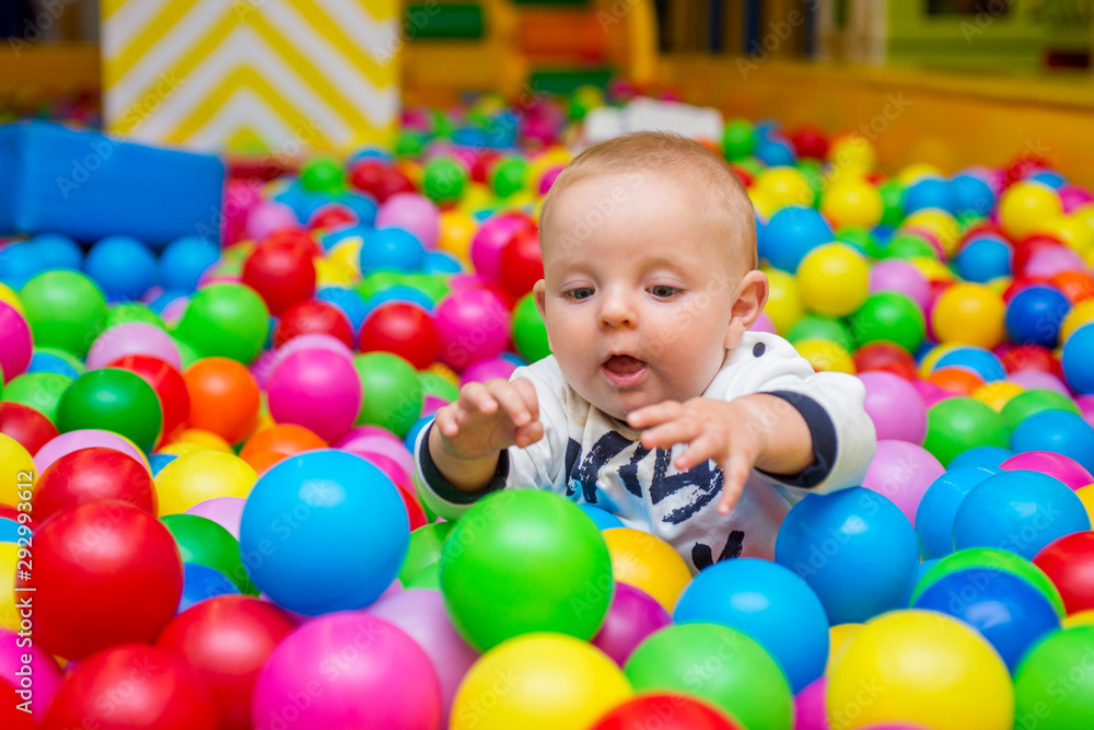 Playground with ball pit indoor. Joyful small kid having fun at indoor play center. Child is playing with colorful balls in playground ball pool. Holiday or birthday Playground with ball pit indoor. Joyful small kid having fun at indoor play center. Child is playing with colorful balls in playground ball pool. Holiday or birthday