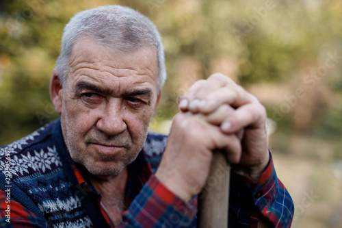 Portrait of caucasian male farmer with shovel digging the land. Old man in the garden.