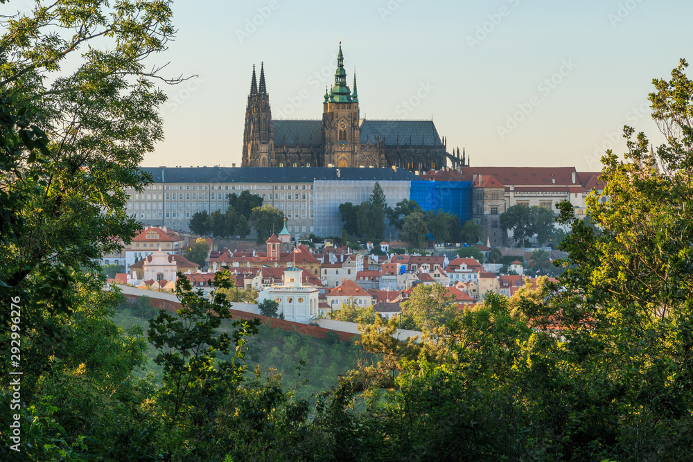 View of Prague Castle with the St. Vitus Cathedral from the viewpoint Petrin in the Mala Strana district on sunny day with blue sky trees and bushes in the foreground
