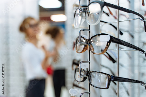 Eyeglasses shop. Stand with glasses in the store of optics. Woman chooses glasses. photo
