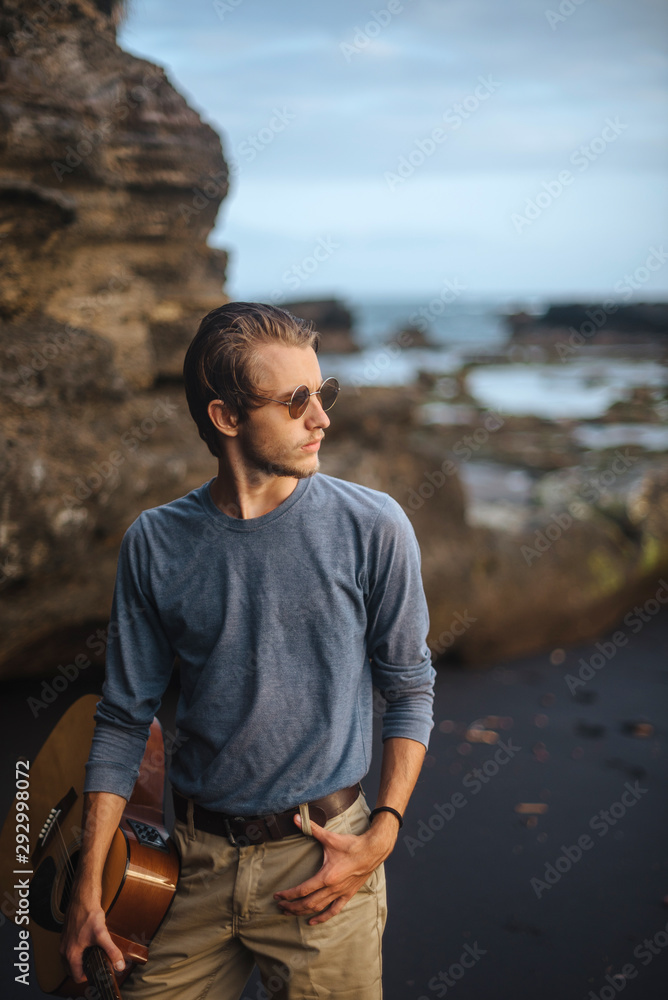 Fototapeta premium Romantic young man with a guitar on the beach