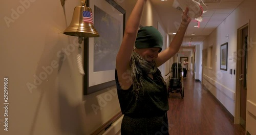 Young woman ringing a bell for finishing her last chemotherapy treatment