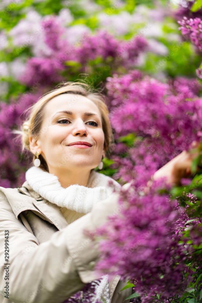 Beautiful blond woman posing outdoors at the blur spring park of violet and white lilac background Beautiful blond woman posing outdoors at the blur spring park of violet and white lilac background