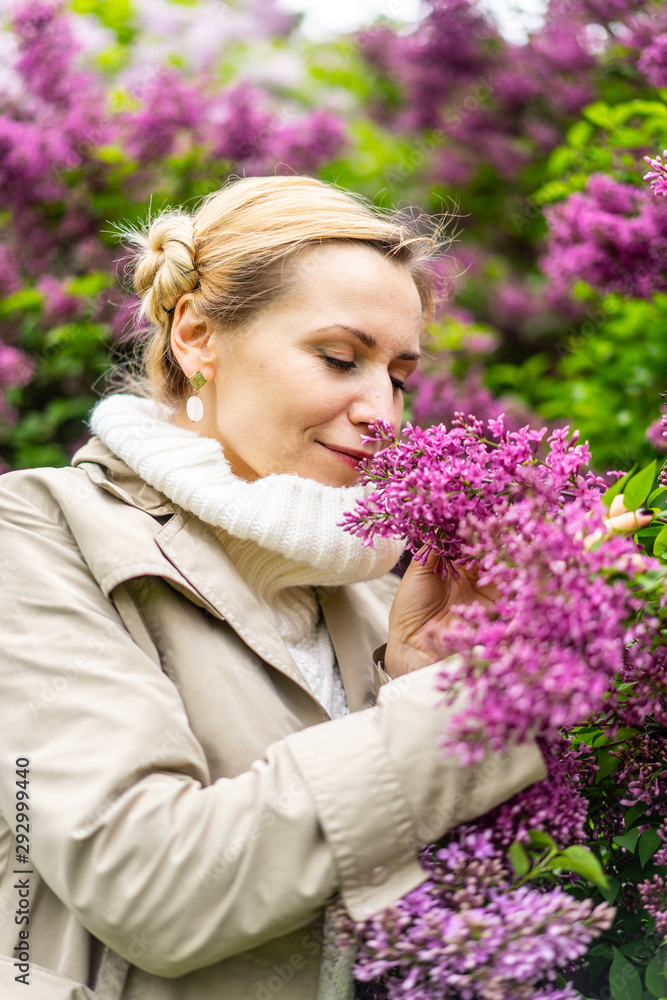 Beautiful blond woman posing outdoors at the blur spring park of violet and white lilac background Beautiful blond woman posing outdoors at the blur spring park of violet and white lilac background