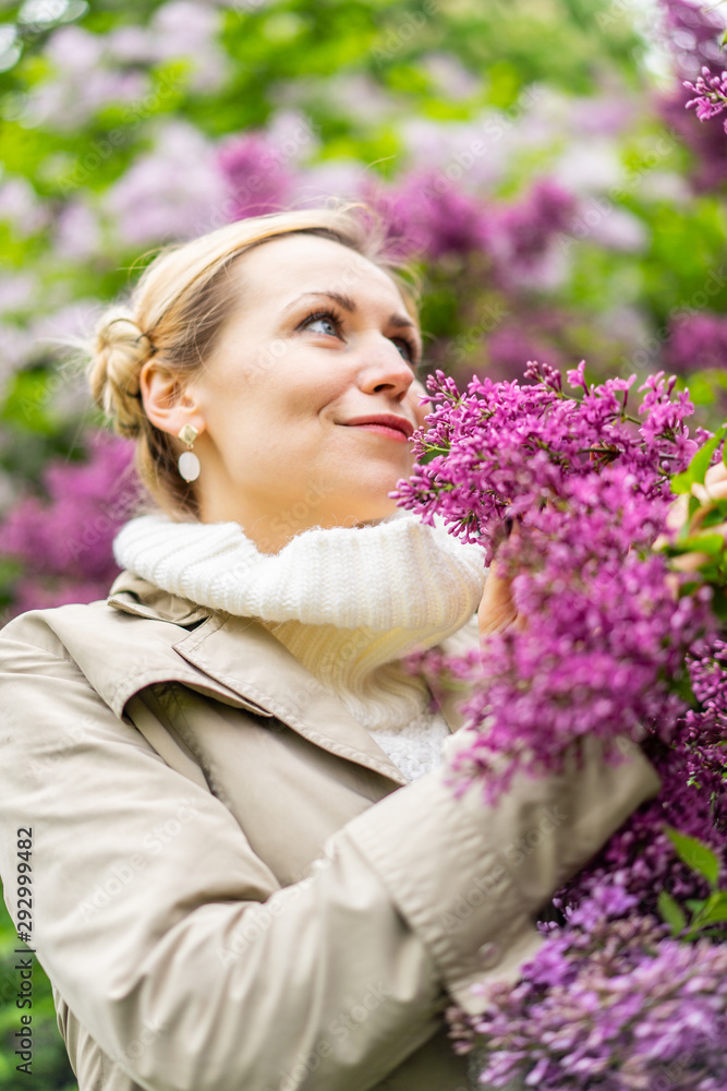 Beautiful blond woman posing outdoors at the blur spring park of violet and white lilac background Beautiful blond woman posing outdoors at the blur spring park of violet and white lilac background