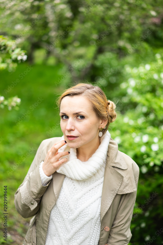 Beautiful blond woman posing outdoors at the blur spring park of violet and white lilac background Beautiful blond woman posing outdoors at the blur spring park of violet and white lilac background