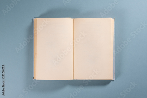 Open blank page book with copy space on blue background.