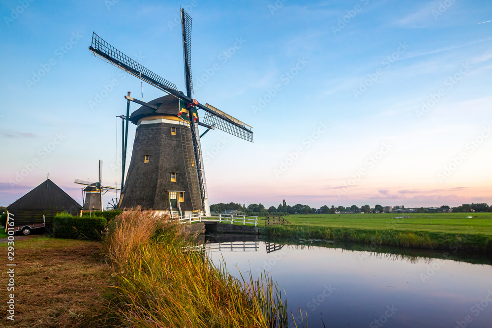 windmill landscape photo with canal and bushes under open blue sky