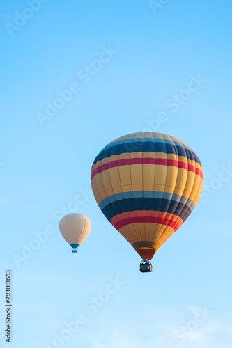 Many colorful hot air balloons flight above mountains - panorama of Cappadocia at sunrise. Wide landscape of Goreme valley in Cappadocia - billboard background for your travel concept in Turkey. © develi