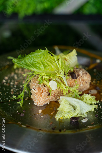 Close up of deep fried Camembert with waffle crumbs, sweet sauce, grated nuts and greens photo