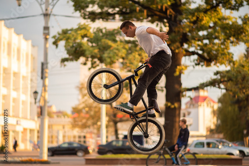 The guy performs a stunt on the BMX, jumping from the parapet high up.