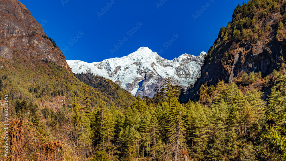 Snow covered mountain peaks in Himalayas, Nepal during bright sunny day with blue sky.	
