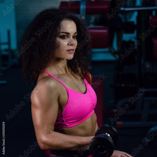 a sexy sports girl is doing workout in a gym. muscular woman. bodybuilding.