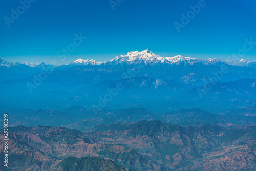 Aerial view from a plane over Himalaya mountains on a bright sunny morning.