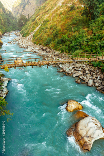 River flows trough rocky valley in Himalaya mountains in Nepal during sunny summer day. 