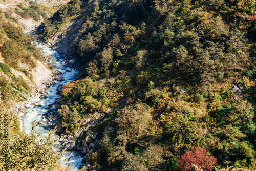 River flows trough rocky valley in Himalaya mountains in Nepal during sunny summer day. 