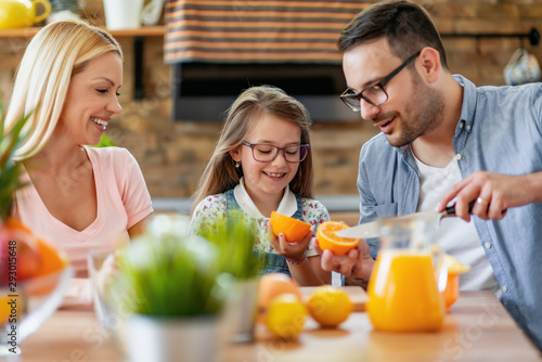 Happy family makes orange juice for breakfast