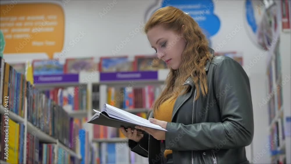 Portrait of a Young Beautiful Woman with Bright Red Hair in Glasses, Pretty Girl Reading in Book Library University. Portrait of a Young Beautiful Woman with Bright Red Hair in Glasses, Pretty Girl Reading in Book Library University.