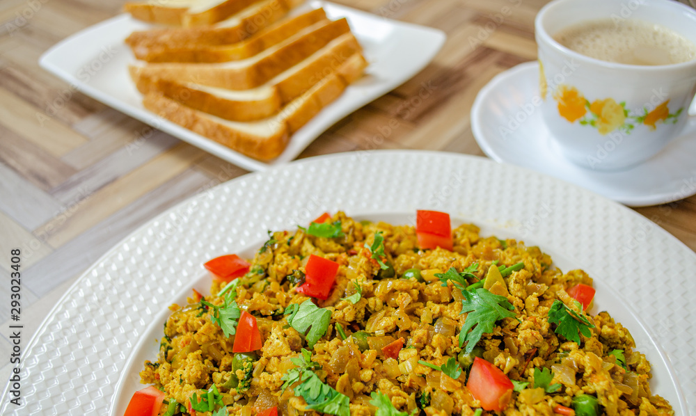 Egg Bhurji with coriander leaves and coconut along with bread and tea. Close up of a typical Indian breakfast.