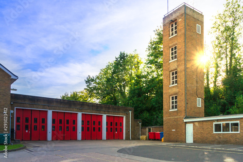 Facade of old fire station with red gates and tower close up against the background of the summer sky