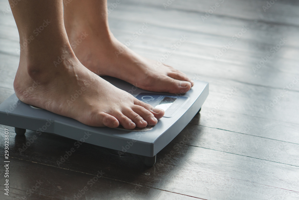 Fototapeta premium Woman measuring weight on weight scale have a copy space for text.