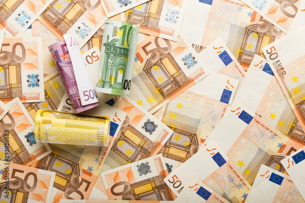 Rolls of euro banknotes on scattered euro money. Business, finance, saving, banking concept, exchange rates. Frame, copy space, top view. - obrazy, fototapety, plakaty 