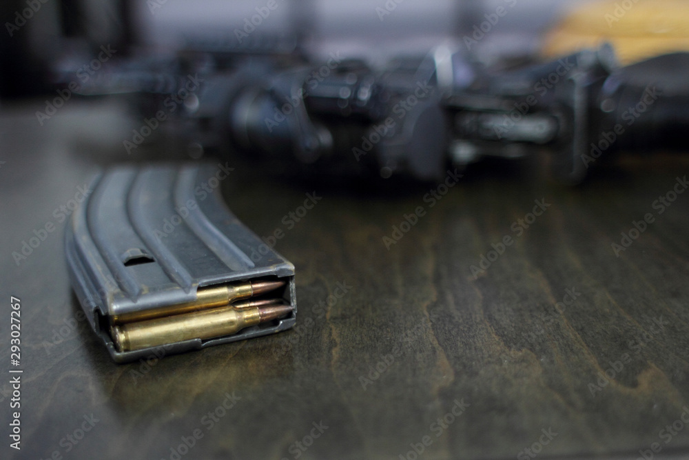 High capacity magazine with bullets next to an AR15 on a table in a home. High capacity magazine with bullets next to an AR15 on a table in a home.
