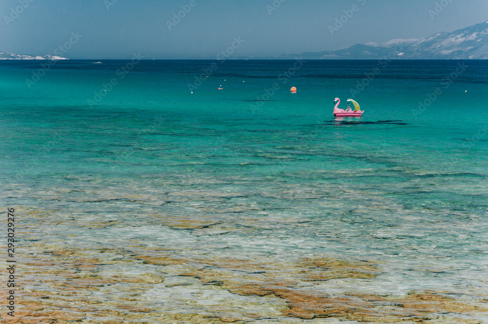 Aerial shot of beautiful blue lagoon at hot summer day with sailing boat. Top view of people are swimming around the boat.