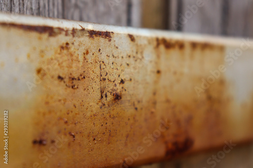 rusty metal beam on back of wooden fence