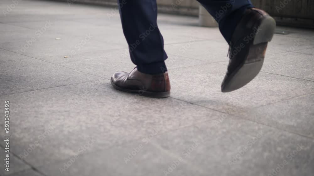 Close-up of the shoes of a walking businessman on the street Close-up of the shoes of a walking businessman on the street