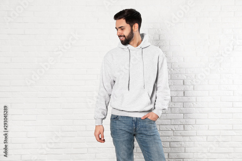 Portrait of young man in sweater at brick wall. Mock up for design