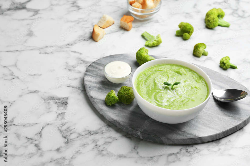 Bowl of broccoli cream soup served on white marble table, space for text Bowl of broccoli cream soup served on white marble table, space for text