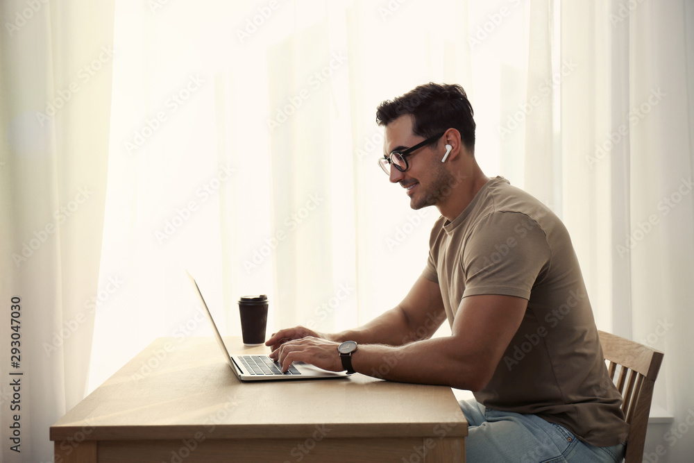 Portrait of young man with laptop at table indoors