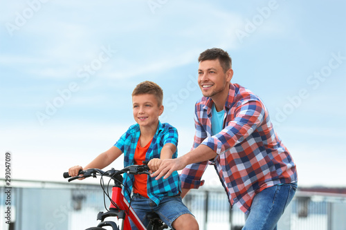 Dad teaching son to ride bicycle outdoors