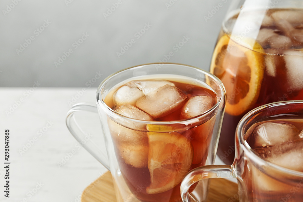 Cups and jug of refreshing iced tea on light table Cups and jug of refreshing iced tea on light table