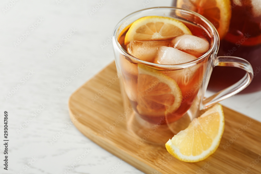 Cup and jug of refreshing iced tea on white table Cup and jug of refreshing iced tea on white table