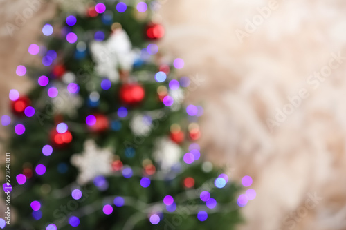 Beautiful Christmas tree with lights against brown background, blurred view. Space for text
